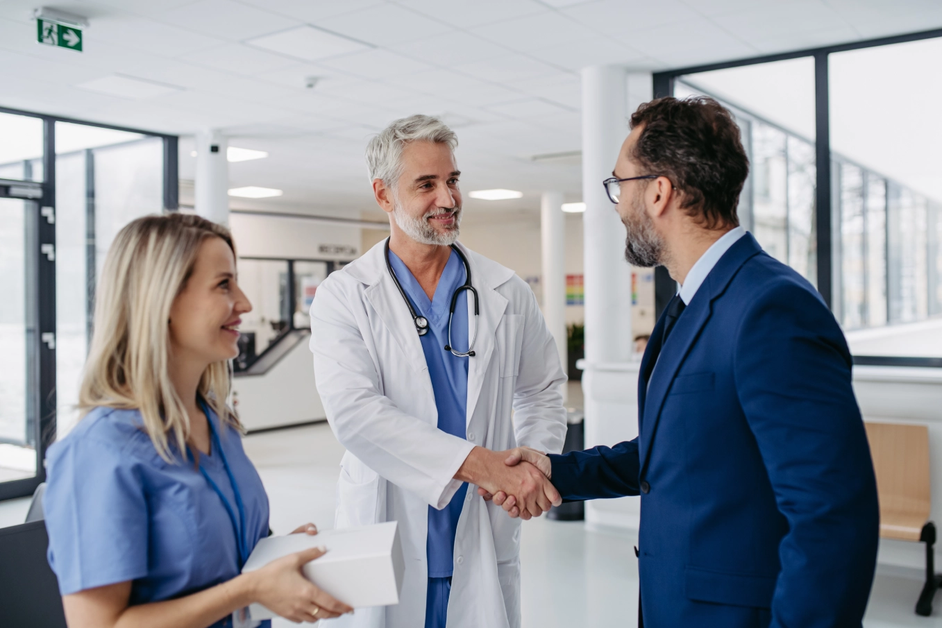 Doctor and businessman shaking hands in hospital.