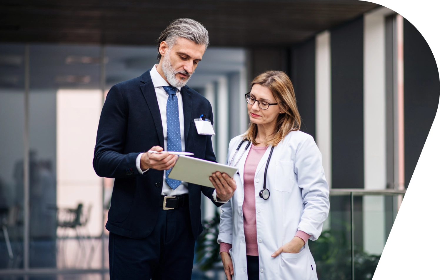 A man and woman in business attire looking at a tablet.